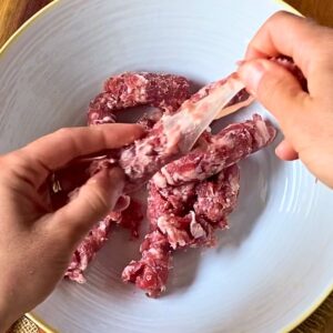 Removing the casing from fresh Italian sausage.
