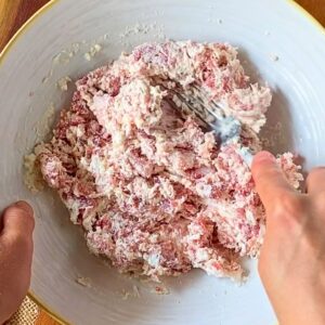 Mashing sausage and cream cheese together with a fork for crostone filling.