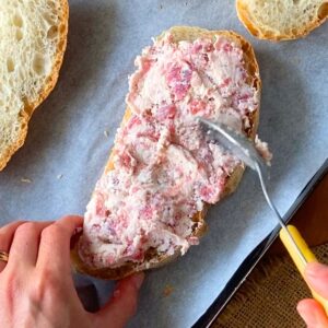 Spreading the sausage and cheese mixture onto rustic bread.